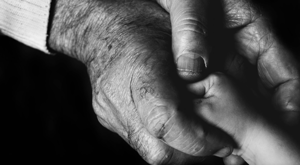 weathered human hands holding a small child's hand